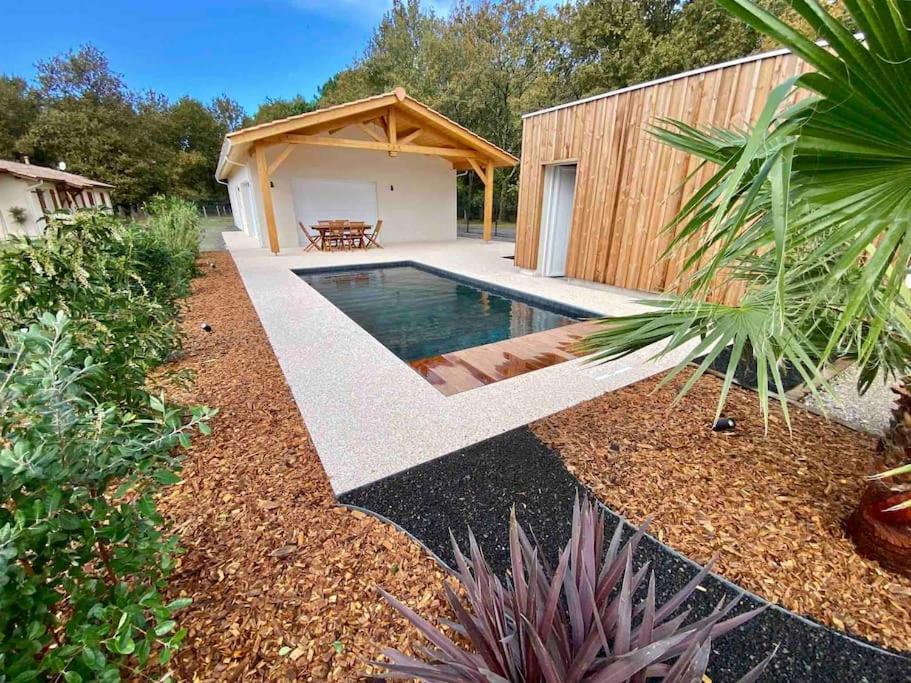 een achtertuin met een zwembad en een huis bij Magnifique maison proche lac avec piscine chauffée in Sanguinet
