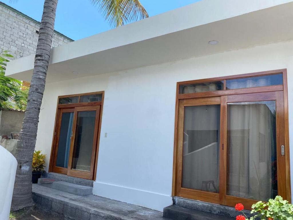 a white house with wooden doors and a palm tree at Penguin House in Puerto Villamil