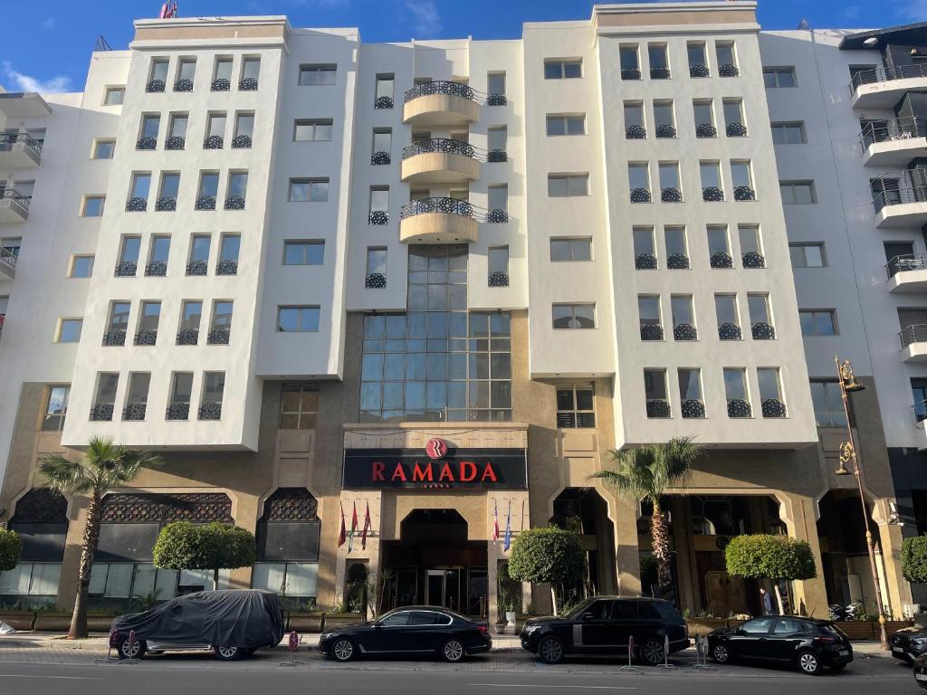 a large white building with cars parked in front of it at Ramada By Wyndham Fes in Fès