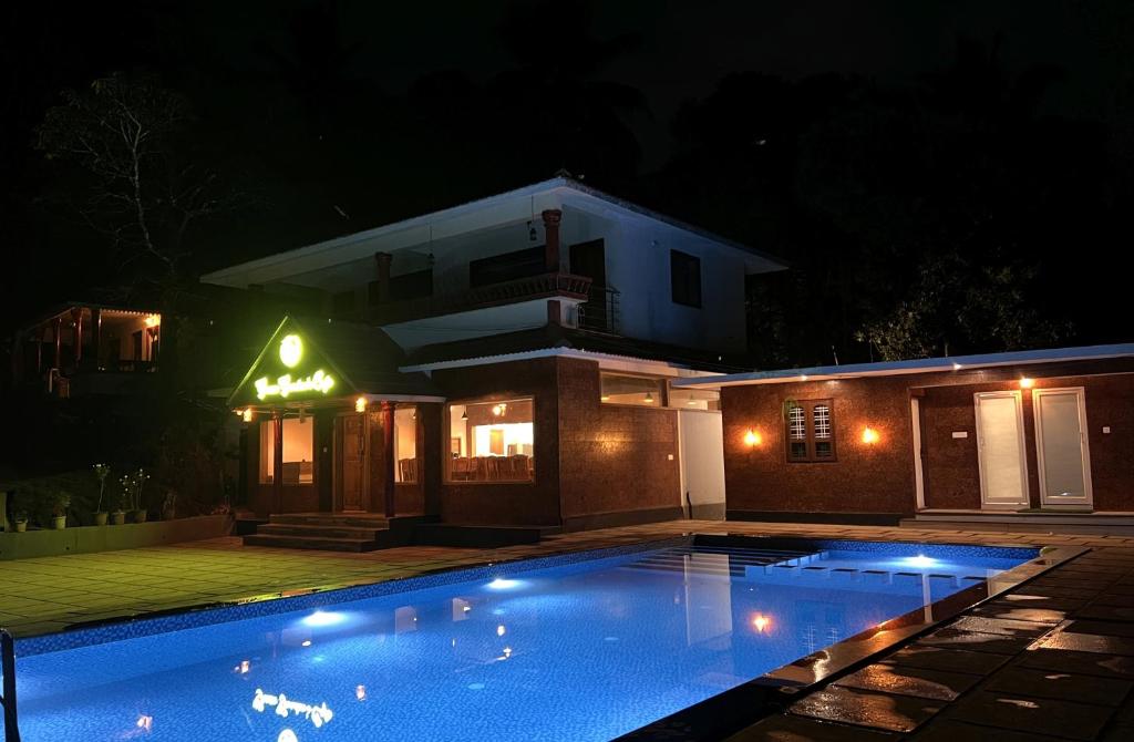 a swimming pool in front of a house at night at Green Garden Deluxe Room in Vayittiri