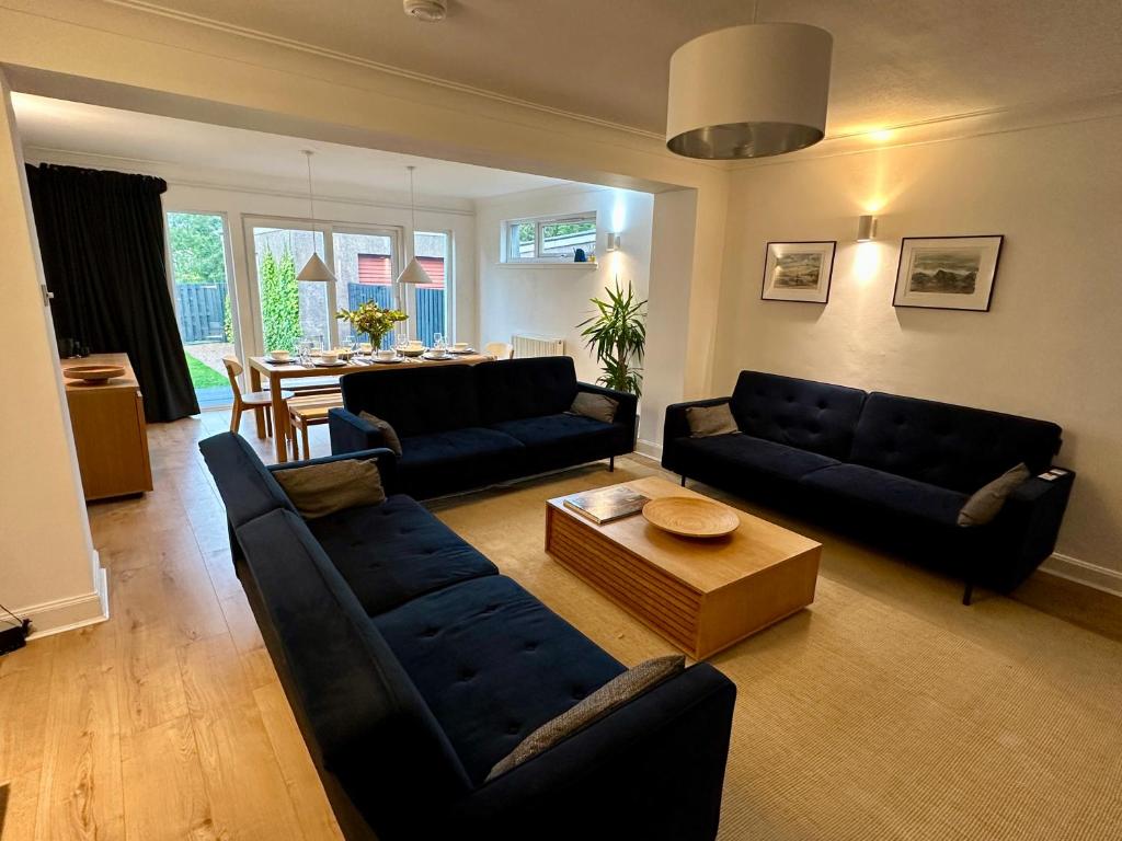 a living room with two black couches and a table at Lovely house & garden, short walk to town & beach. in Fife