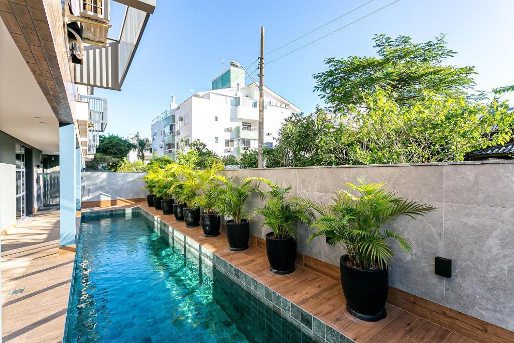 a swimming pool with potted plants on a fence at Apto moderno prédio novo em Jurerê JPR212 in Florianópolis