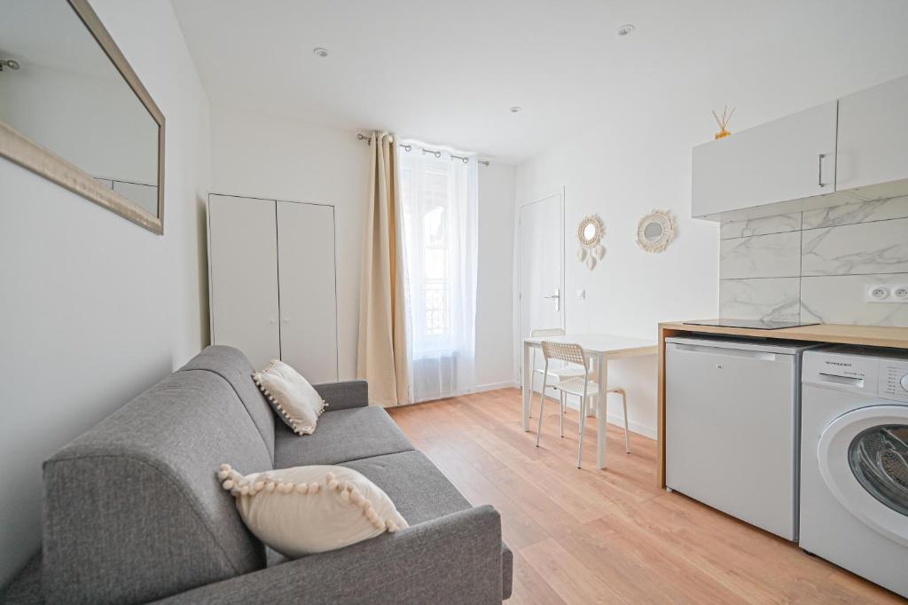 Il comprend un salon avec un canapé gris et une cuisine. dans l'établissement Appartement cosy, neuf et tout equipé, à 3mn à pied de Paris, à Clichy