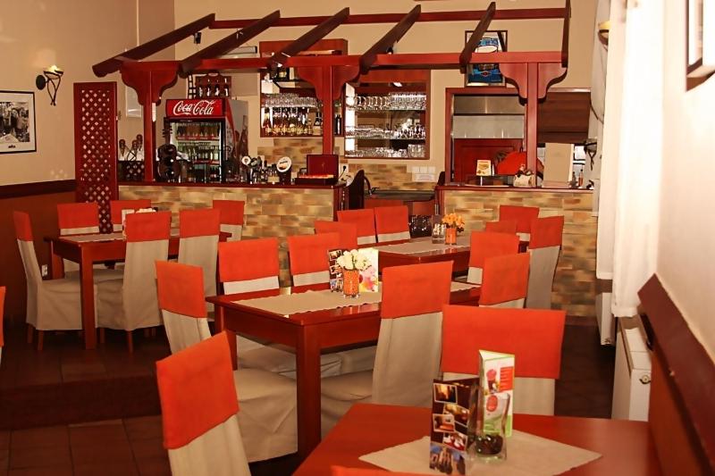 a restaurant with red chairs and tables and a bar at Olymp penzion in Komárno