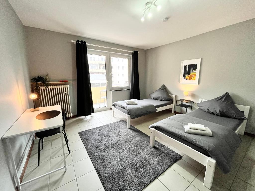 een slaapkamer met 2 bedden, een bureau en een raam bij Apartment Central 10E 90qm Wi-Fi free Parking calm back house in Dortmund