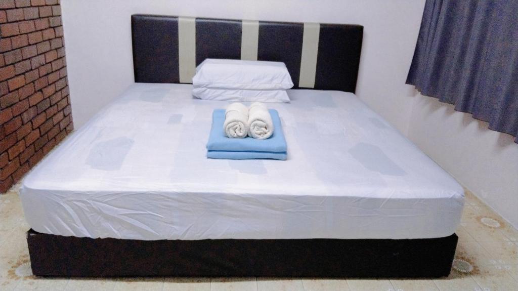 a bed with two towels and towels on it at Happy Bentong Guest House in Bentong