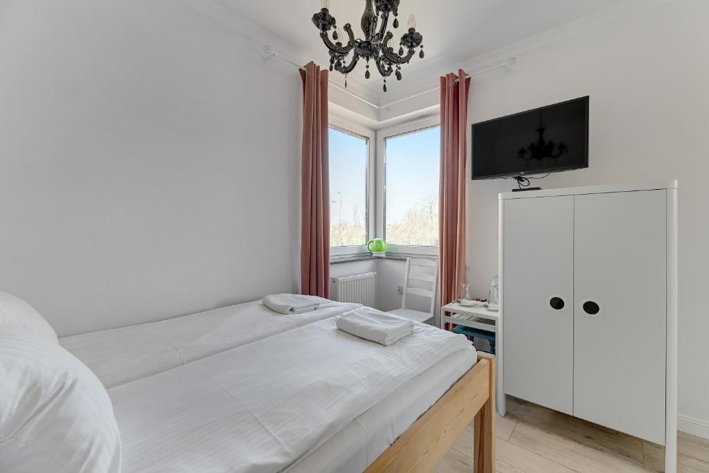 a white bedroom with a bed and a window at Szafarnia in Gdańsk