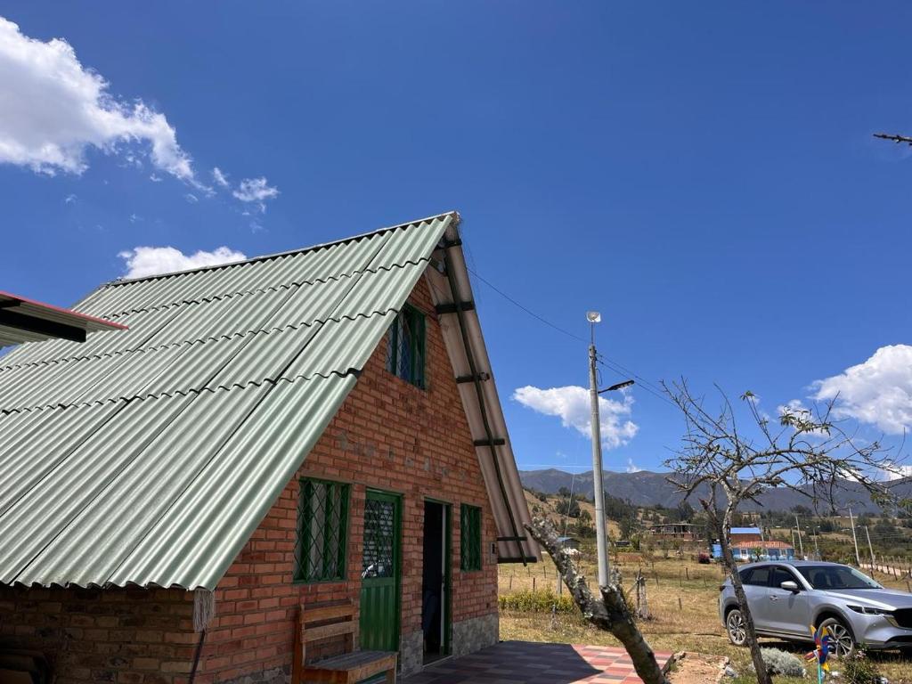 un bâtiment avec un toit et une voiture garée à côté dans l'établissement La cabaña, a 15 minutos de Paipa, à Sotaquirá