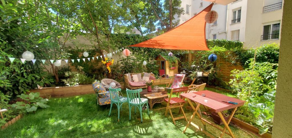 een patio met een tafel en stoelen in een tuin bij Grand appartement avec jardin calme et lumineux in Saint-Ouen