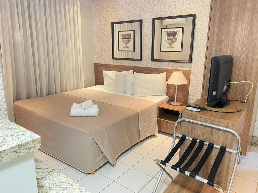 a hotel room with a bed and a television at Sun Square Suítes Hotel By Lual in Goiânia