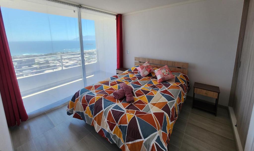 a bedroom with a bed with pillows and a large window at Departamento ejecutivo in Antofagasta