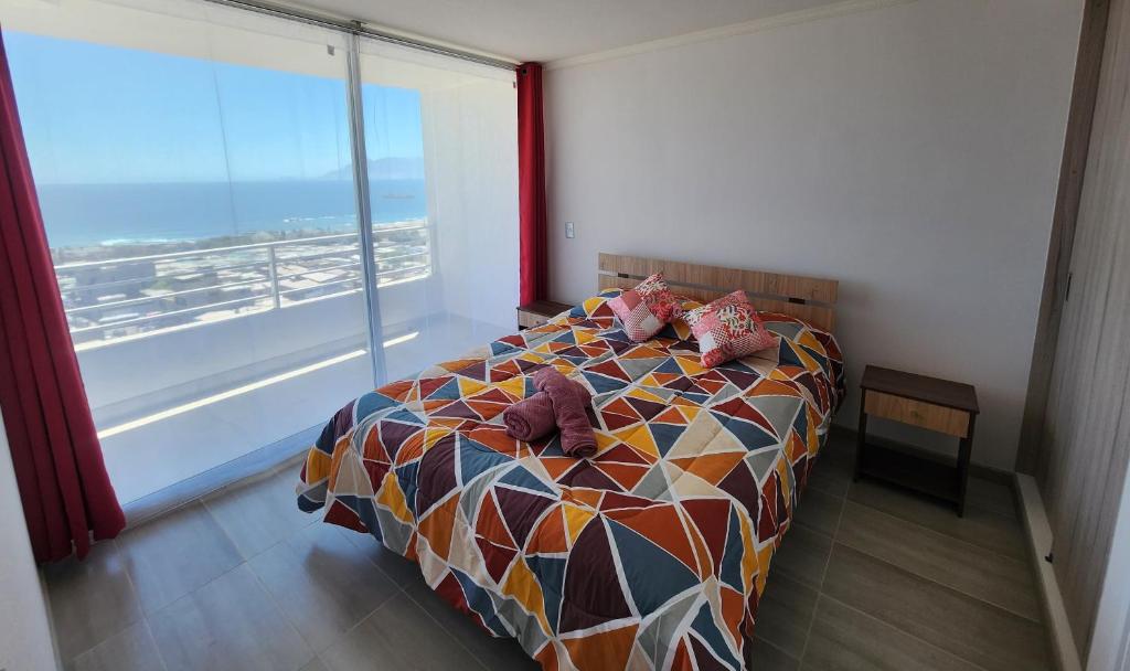 ein Schlafzimmer mit einem Bett mit Kissen und einem großen Fenster in der Unterkunft Departamento ejecutivo in Antofagasta