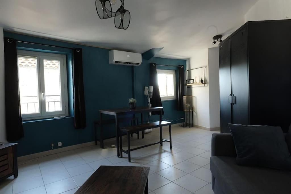 een woonkamer met een tafel en een blauwe muur bij Appartement centre ville de Pierrelatte' in Pierrelatte