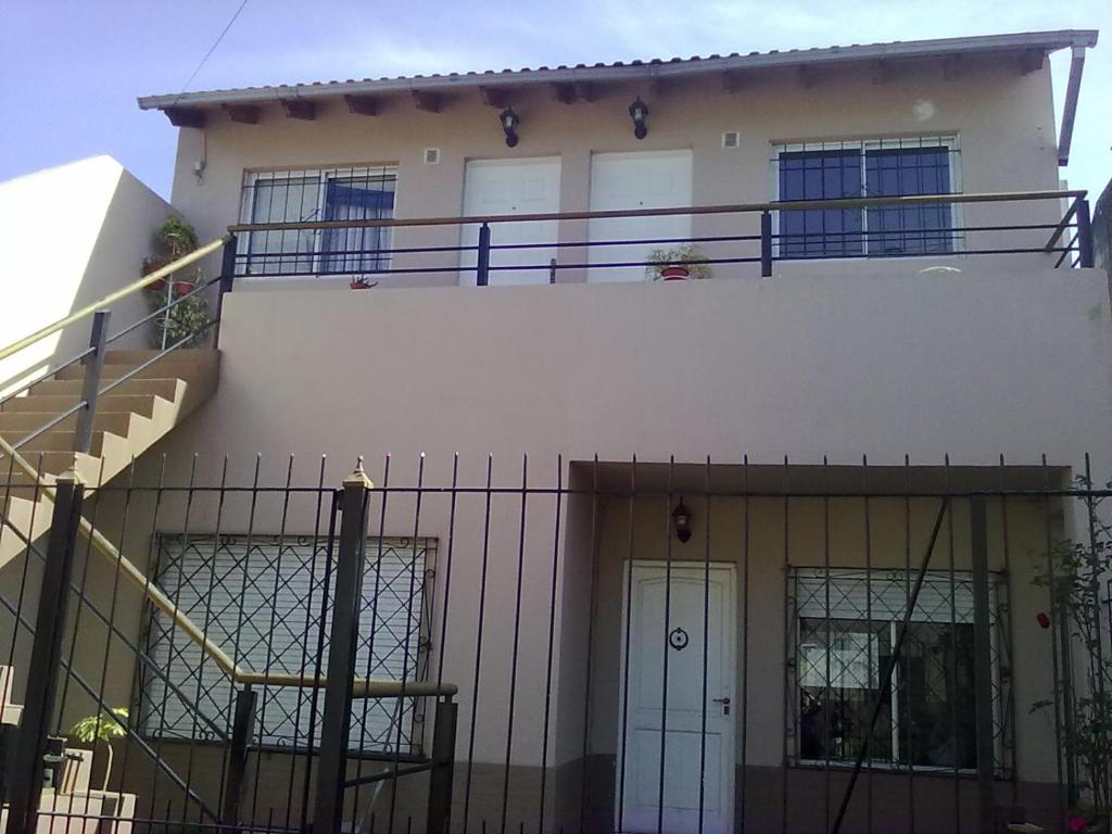uma casa branca com uma varanda em cima em Alojamiento temporario em Lanús