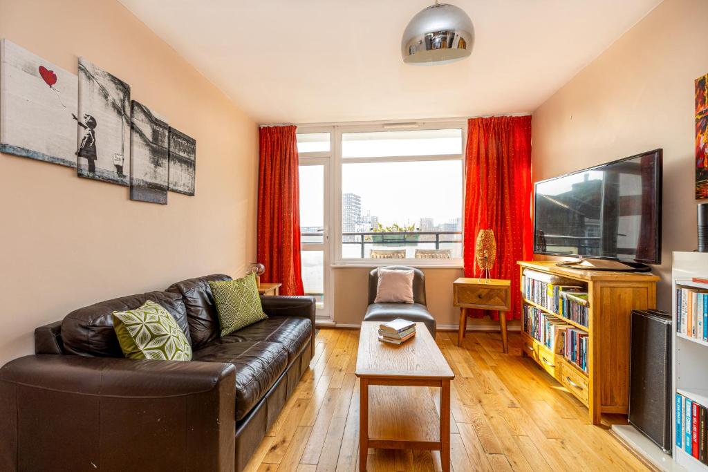 a living room with a leather couch and a tv at 2BR wbalcony, Battersea, 5min Clapham Junction St in London