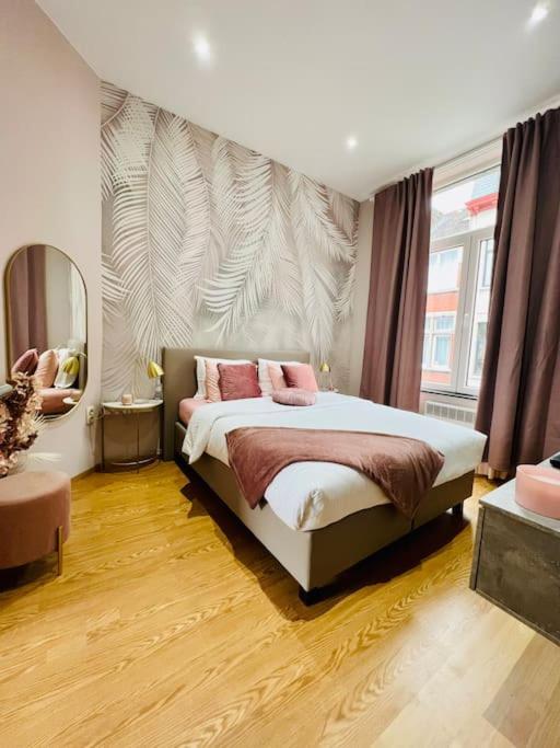 ein Schlafzimmer mit einem Bett mit zwei rosa Kissen in der Unterkunft Charmant petit appartement. in Lüttich