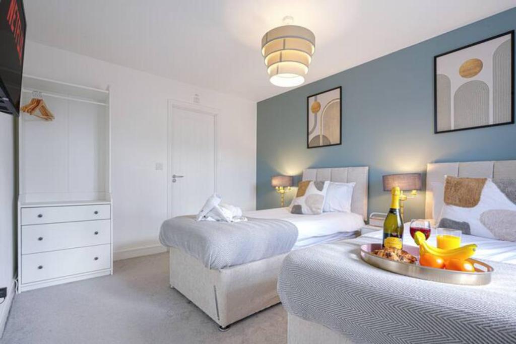 a bedroom with two beds and a table with a bottle of wine at Glebe House - 5 Bedroom 3.5 Bathroom - Sleeps 10 - Driveway Parking, Fast Wifi, SmartTVs with SkyTV, Xbox and Netflix by Yoko Property in Milton Keynes