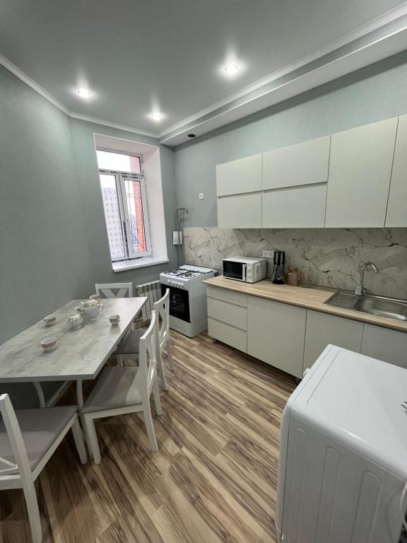 eine Küche mit weißen Schränken sowie einem Tisch und Stühlen in der Unterkunft квартира in Aqtau