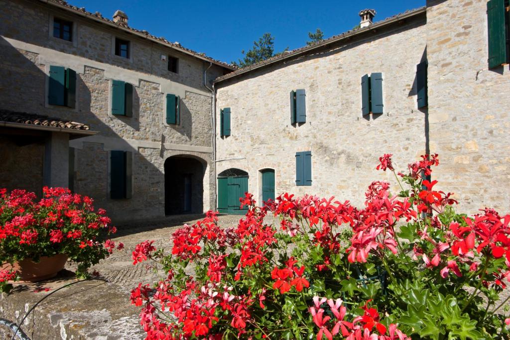 a stone building with red flowers in front of it at B&B CorteBonomini entire home 