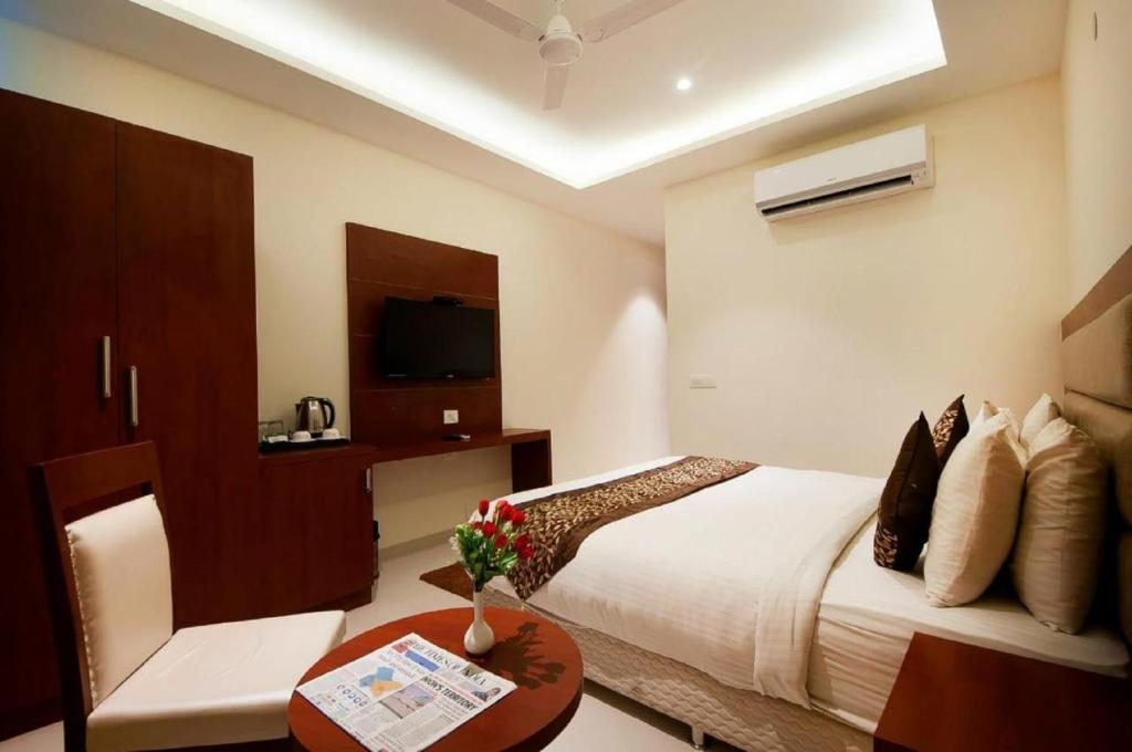 a hotel room with a bed and a table and a tv at Bonito Rooms- Home Stay in Ecotech-III in Greater Noida