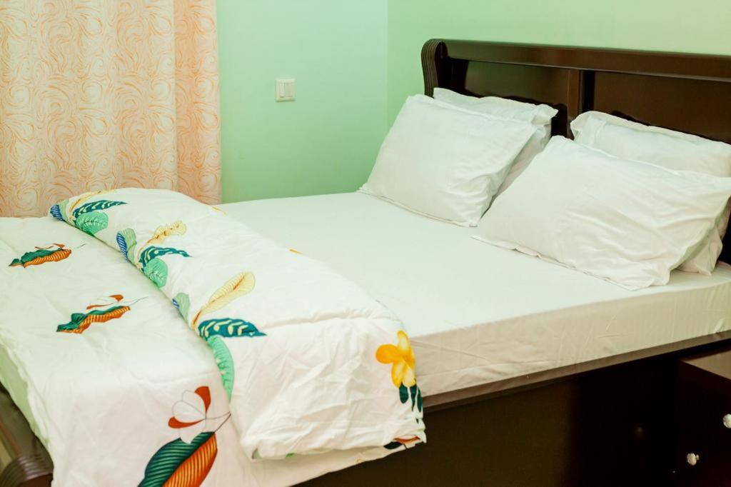uma cama com lençóis brancos e almofadas em Dodoma furnished Apartment em Dodoma