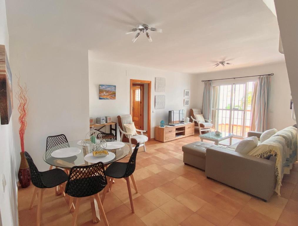 ein Wohnzimmer mit einem Sofa, einem Tisch und Stühlen in der Unterkunft islantilla ático 1 linea de playa vistas al mar in Islantilla