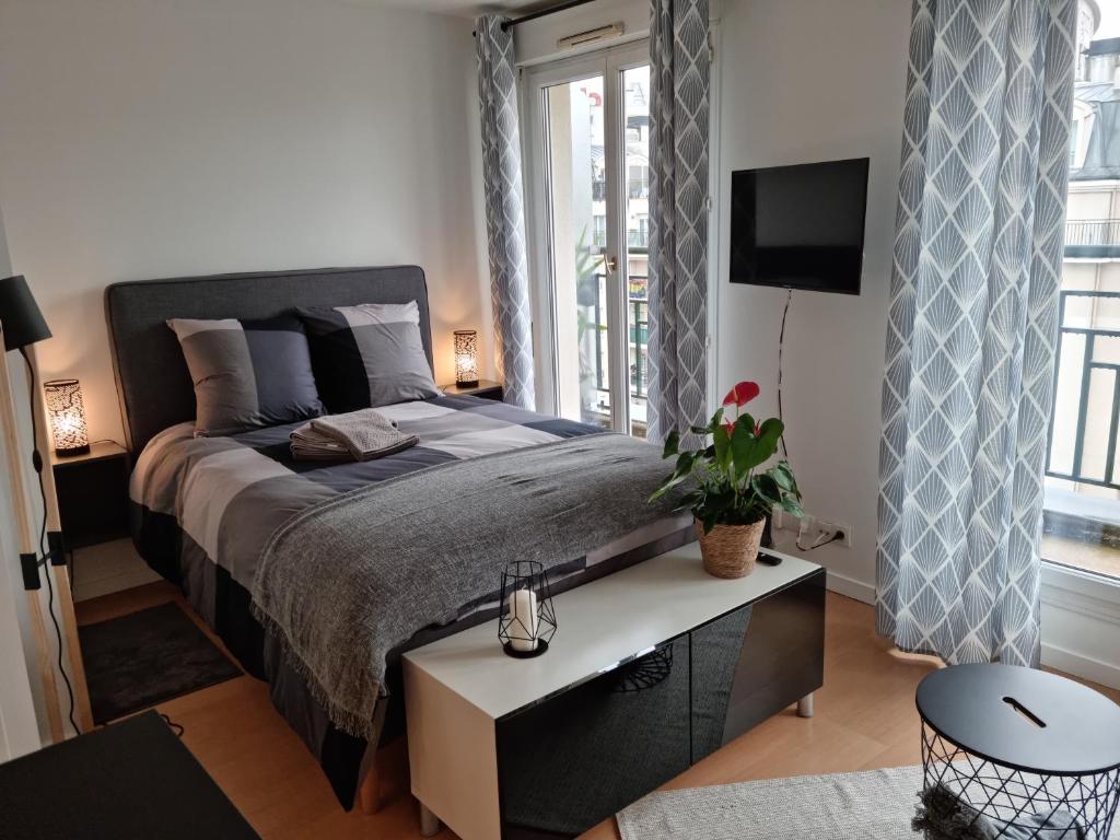 - une chambre avec un grand lit et une télévision dans l'établissement Issy-les-Moulineaux : Studio rénové, à Issy-les-Moulineaux