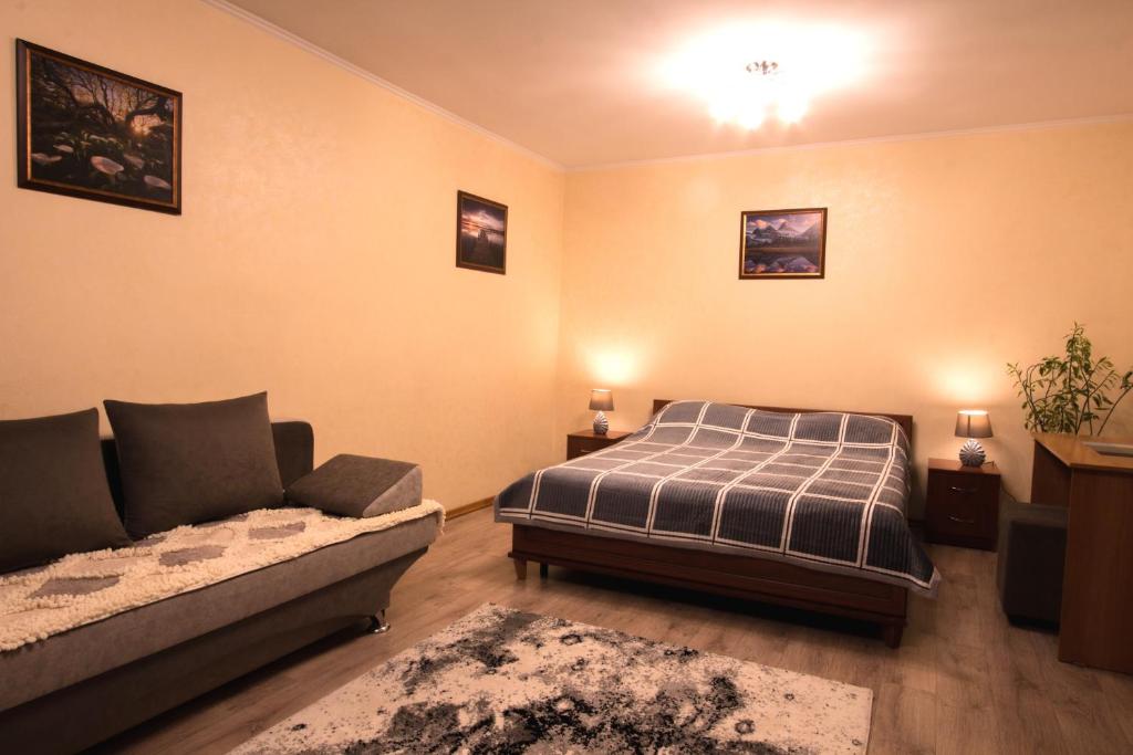 Nadezhda Apartments at Kabanbay Batyr 79 في ألماتي: غرفة معيشة مع سرير وأريكة