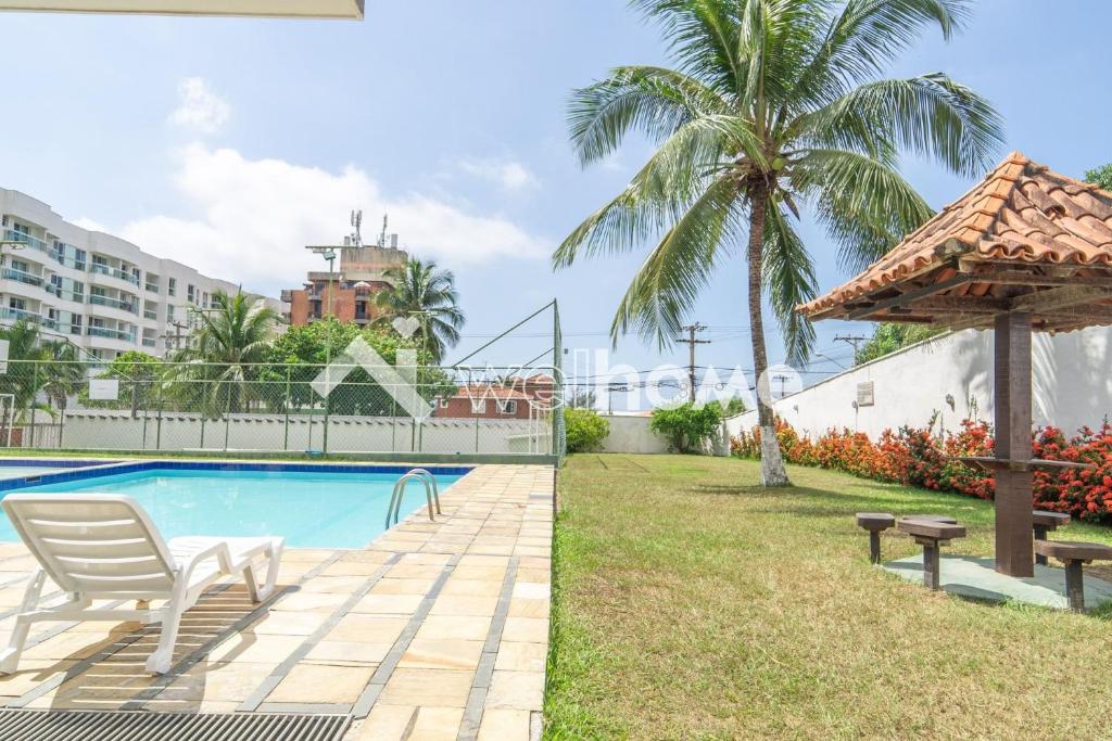 a villa with a swimming pool and a palm tree at Apartamento a 300m da Praia do Forte em Cabo Frio in Cabo Frio