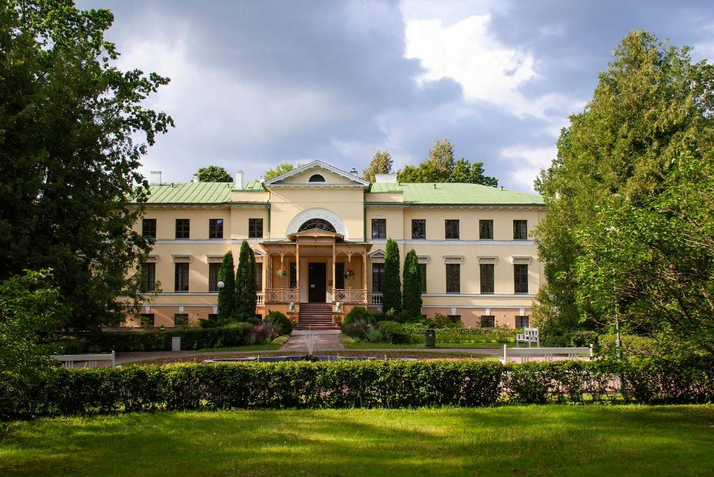 un gran edificio blanco con techo verde en Naukšēnu muiža, en Naukšēni