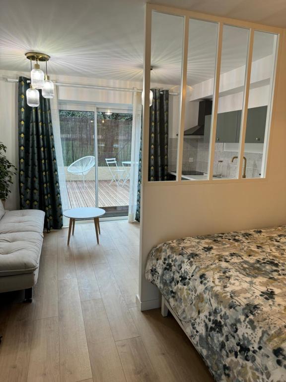 a bedroom with a bed and a couch and a table at L'Écrin de Marie-Lou Studio Cosy in Chaponost