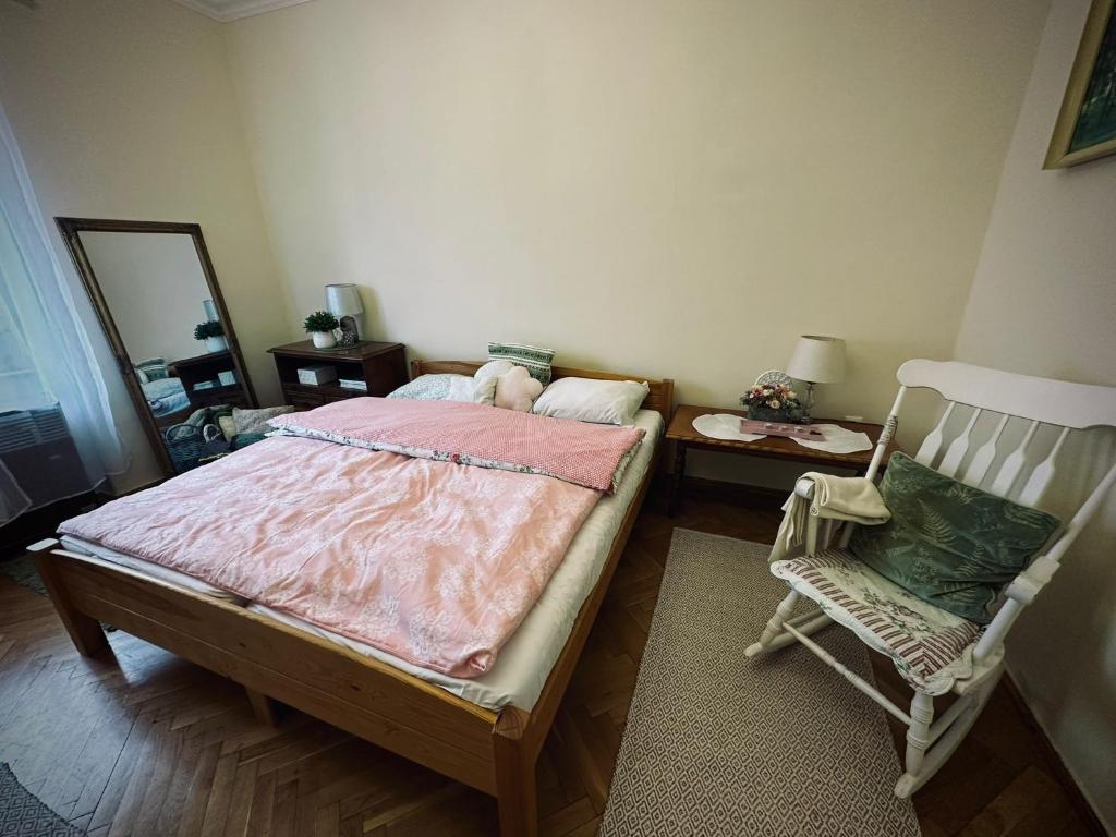 une chambre avec un lit, une chaise et un miroir dans l'établissement Tabán Apartman, à Pécs