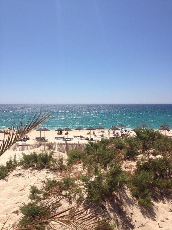 a beach with chairs and umbrellas and the ocean at Comporta House in Comporta