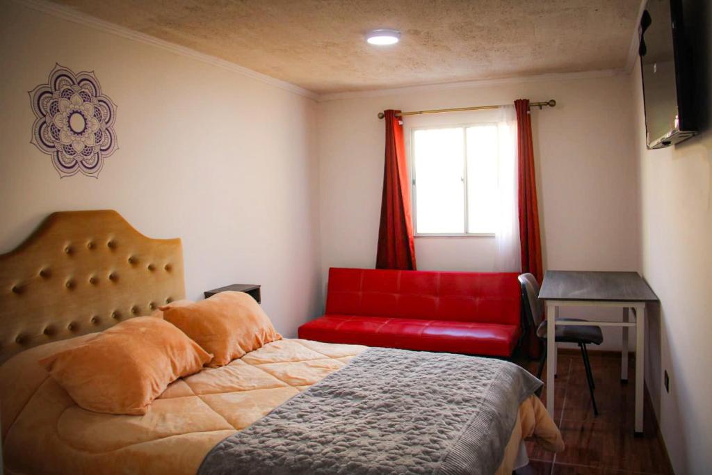 a bedroom with a red bed and a red couch at Killary Apart Hotel in Antofagasta