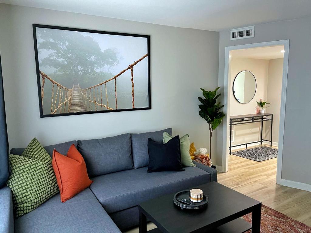 a living room with a blue couch with a bridge painting at *NEW* The Cozy Haven, 5 minutes to ATL airport in Atlanta