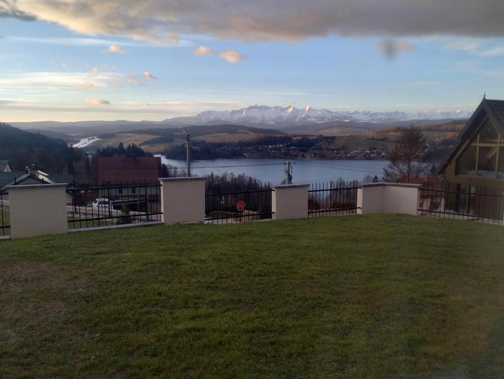 a yard with a view of a lake and mountains at Widokowy Zakątek in Czorsztyn