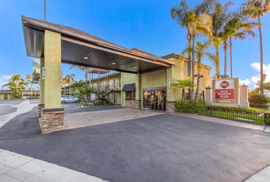 a parking lot in front of a building with palm trees at Best Western Plus Pavilions in Anaheim