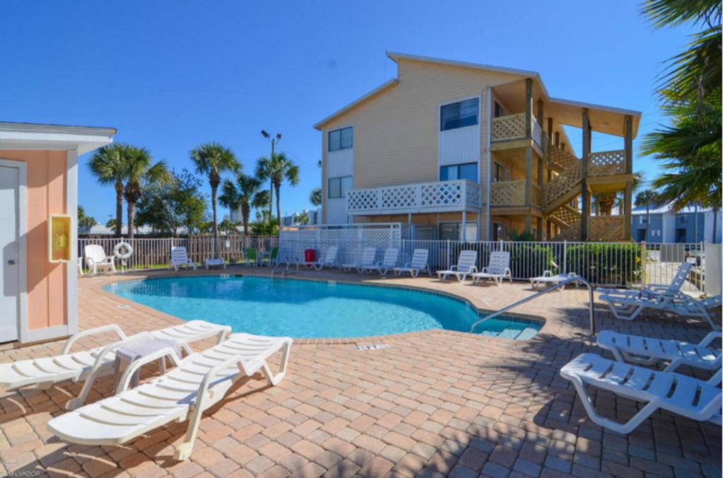 a swimming pool with lounge chairs and a house at Beach Place Seconds to Beach 6 in Panama City Beach