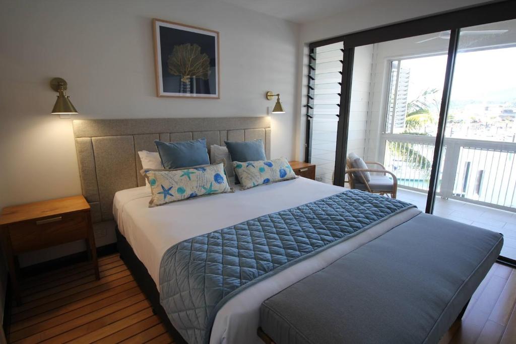 um quarto com uma cama grande e uma janela grande em The Boathouse Apartments em Airlie Beach
