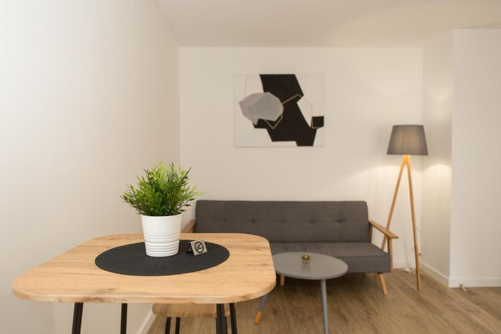 un salon avec un canapé et une table avec une plante en pot dans l'établissement Appart cozy rénové proche gares, balcon & parking, à La Madeleine