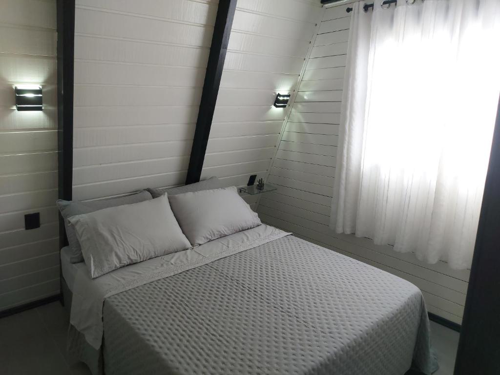 a small bedroom with a bed and a window at Chale Brisa Do Mar in Palhoça