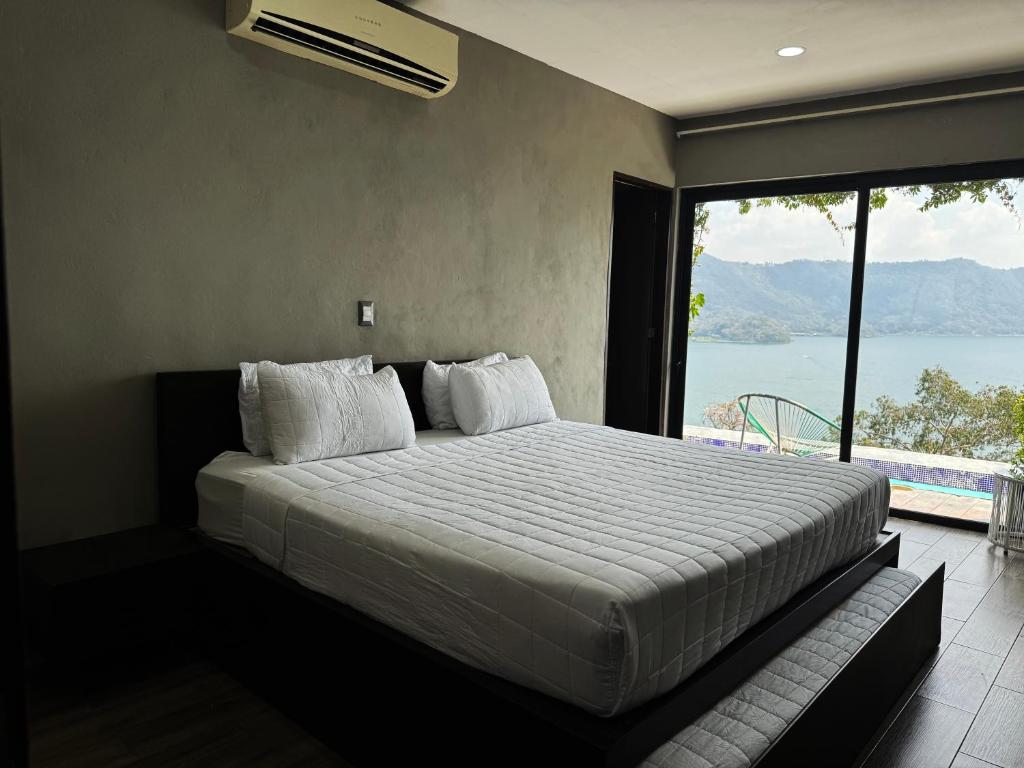 a bedroom with a bed with a view of the water at Cardedeu Hotel Lago de Coatepeque in El Congo