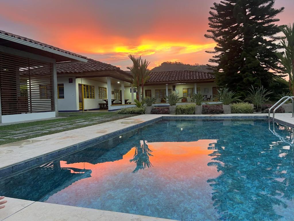 a swimming pool in front of a house with a sunset at The Coffee Club Campestre in Chinchiná