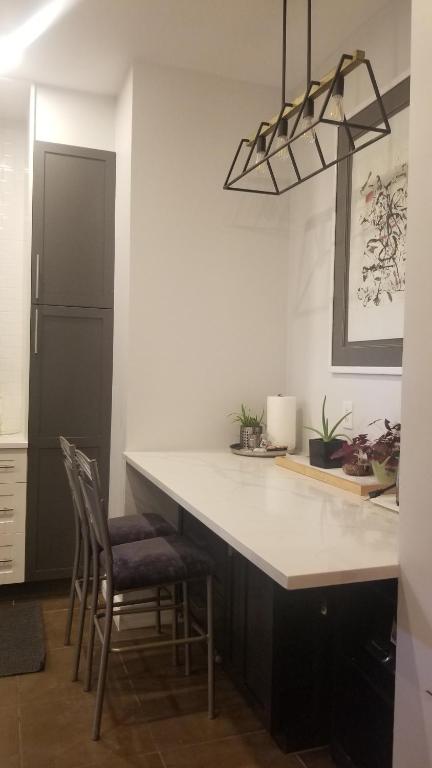 uma cozinha com um grande balcão branco e cadeiras em Tina's gem em Ottawa