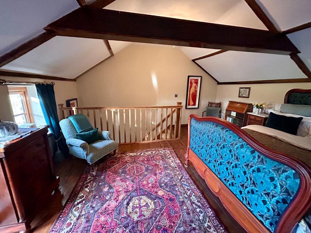 Romantic Country Cottage with log burner, garden patio, outdoor tub and country views- Brecon Beacons National Park في Llangadog: غرفة نوم بسرير وكرسي وسجادة