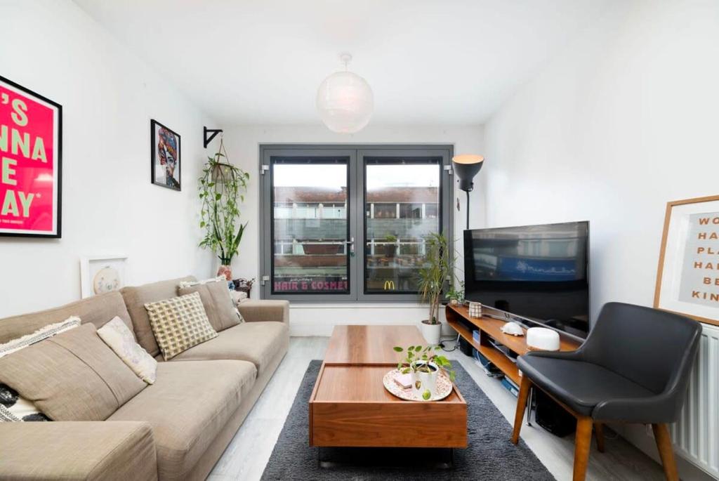 a living room with a couch and a tv at Chic 1BR London Flat with Balcony and Garden Access in London