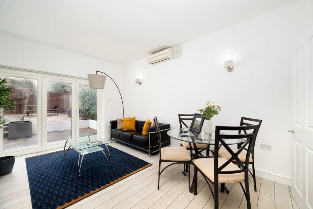 een woonkamer met een tafel en stoelen en een bank bij 2BR 2Baths ground floor garden apartment in Kingston upon Thames
