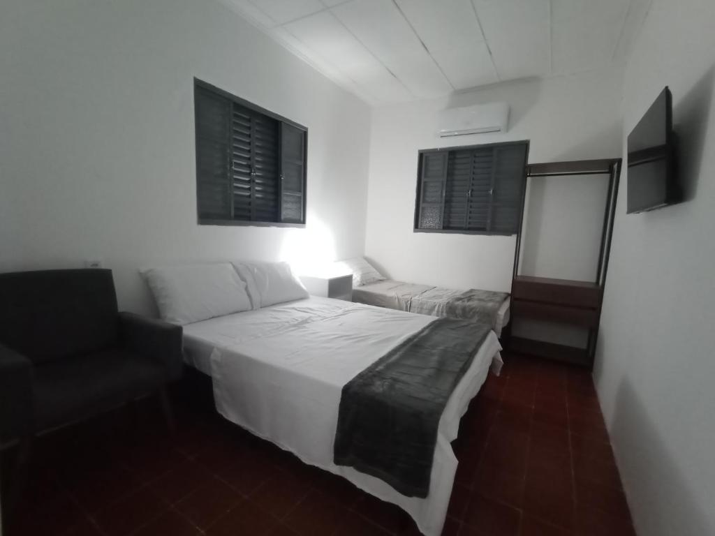 um quarto com uma cama, uma cadeira e 2 janelas em New hotel em Alegrete