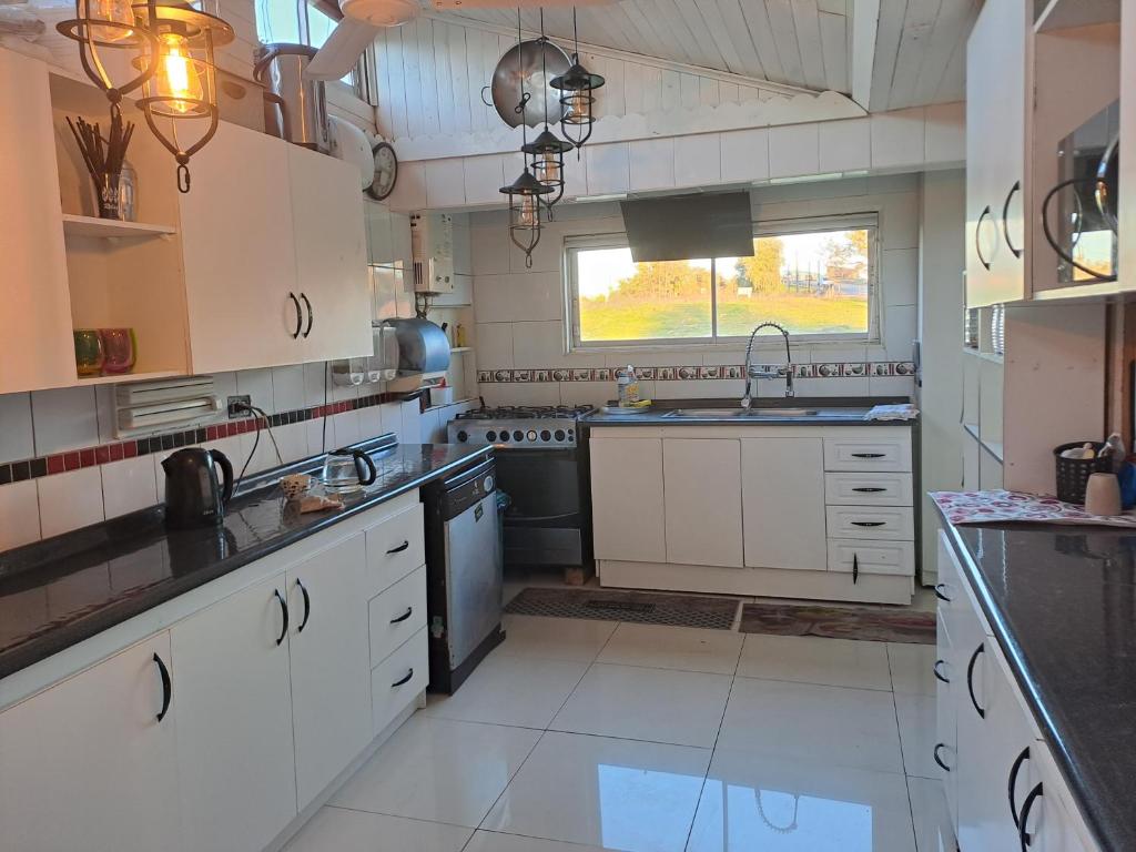 uma grande cozinha com electrodomésticos brancos e uma janela em HOSTAL EL AROMO pensión a empresas em Chillán