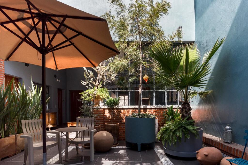 un patio con mesa, sombrilla y plantas en Casa Murmullos en Guadalajara